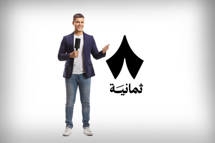 صحفي بجانب شعار منصة ثمانية السعودية