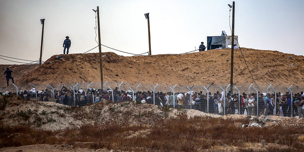 مواطنين فلسطينين من غزة أثناء الانتظار لاستلام المساعدات في المنطقة العازلة برفح مكان وجود مؤسسة غزة الإنسانية